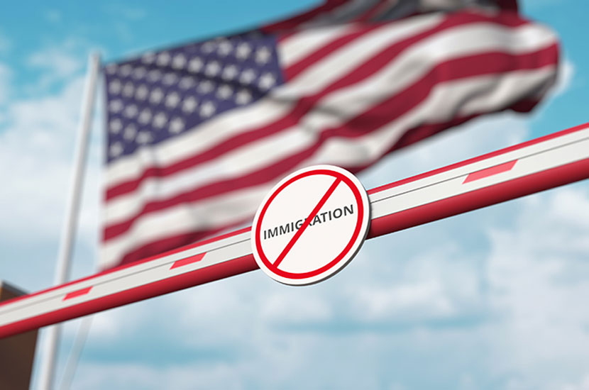 US Border Closure Closed boom barrier with stop immigration sign against the American flag