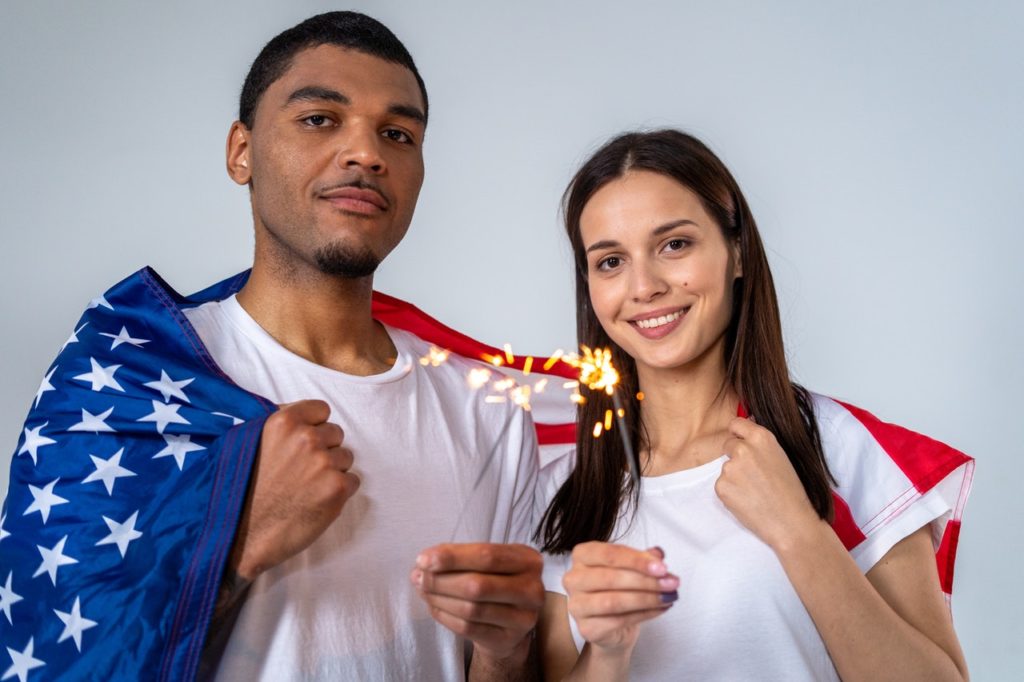 Couple holding sparklers fireworks with the US flag