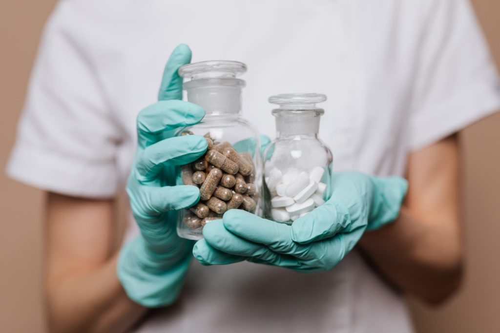Person Holding Clear Glass Jar with Brown and White Medicine